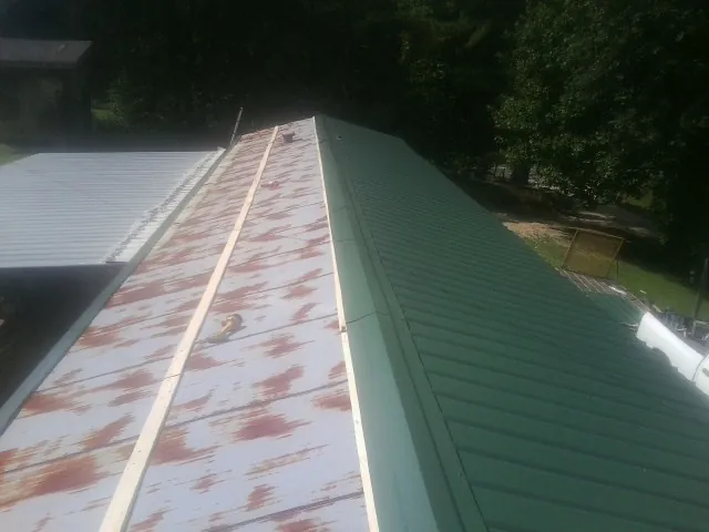 Old rusted panels beside newly installed green metal roofing — Wind Damage Roof Repair by Roofing Brothers in Scottdale