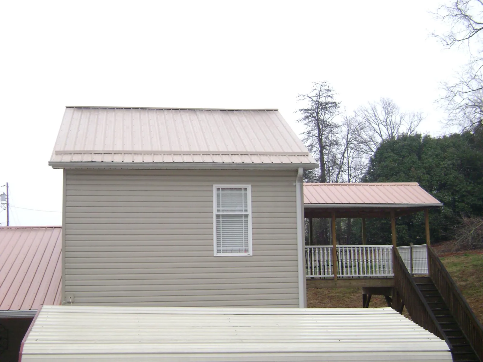 Tan metal roofs on a two story addition and attached porch, from a Roof Replacement job in Scottdale