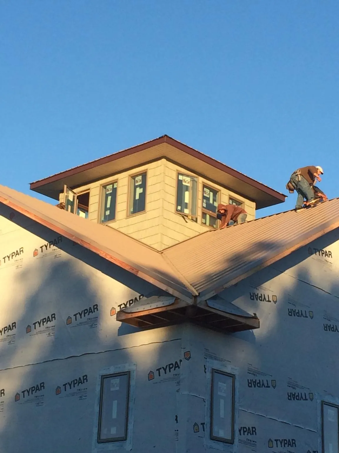 Roofers working around a rooftop cupola on a new metal roof at sunset — Roof Waterproofing in Scottdale by Roofing Brothers
